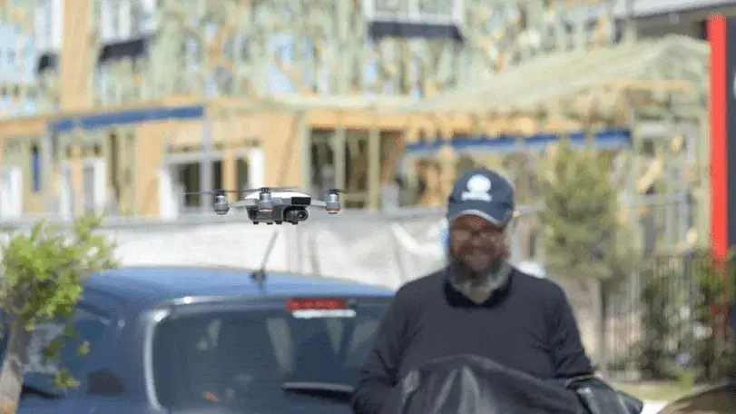 A Mobiddiction team member flying a small survey drone outside a building