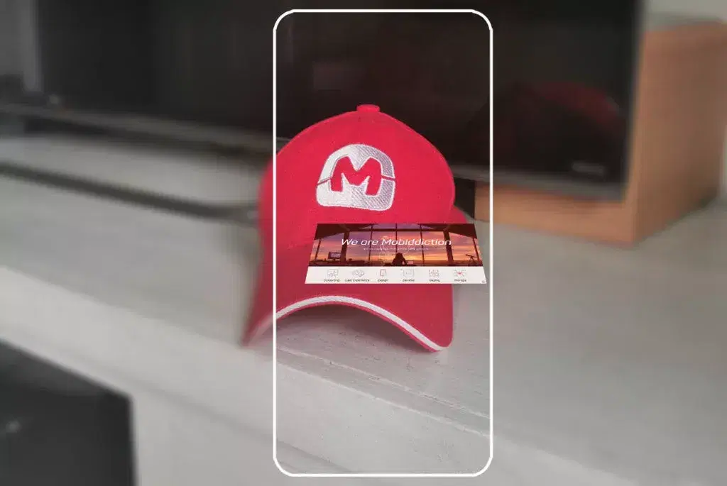 Phone showing a red Mobiddiction cap with an AR information panel anchored in front of it
