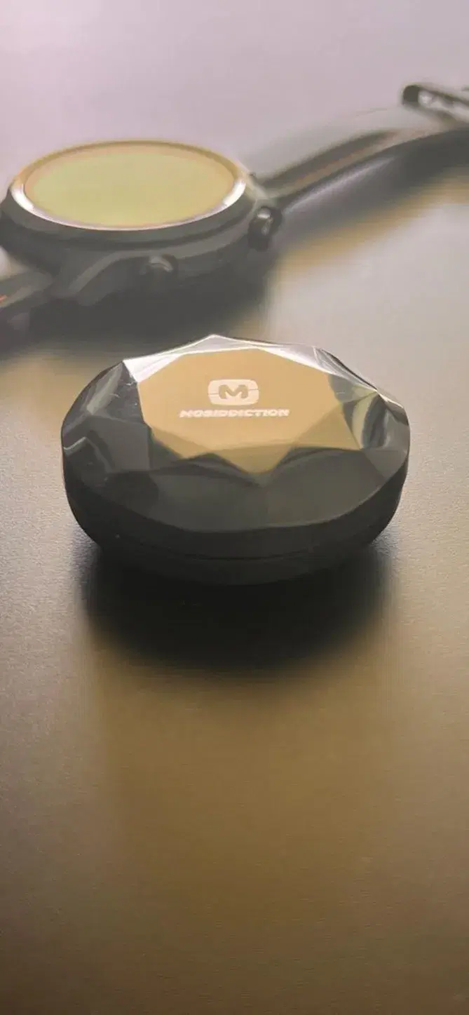 A Bluetooth beacon on a table beside a watch