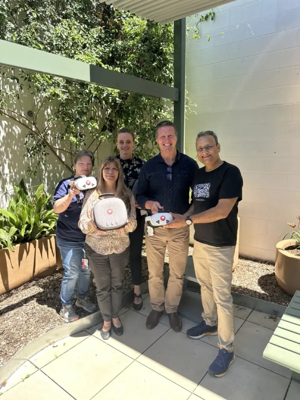 A hospital care team in a courtyard holding the PatientVR headsets for their patients
