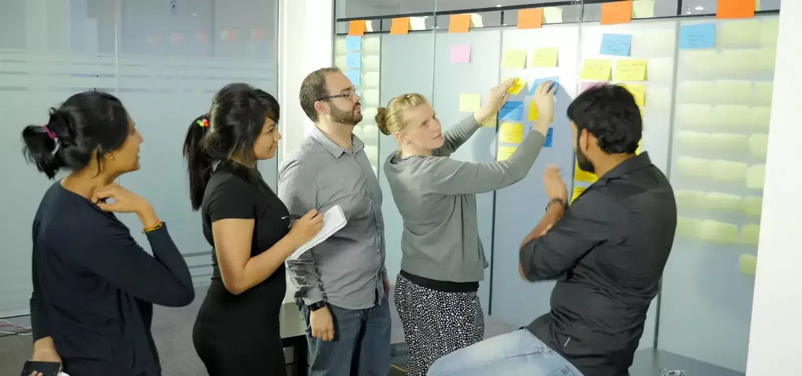 Mobiddiction team members planning at a glass wall covered in sticky notes
