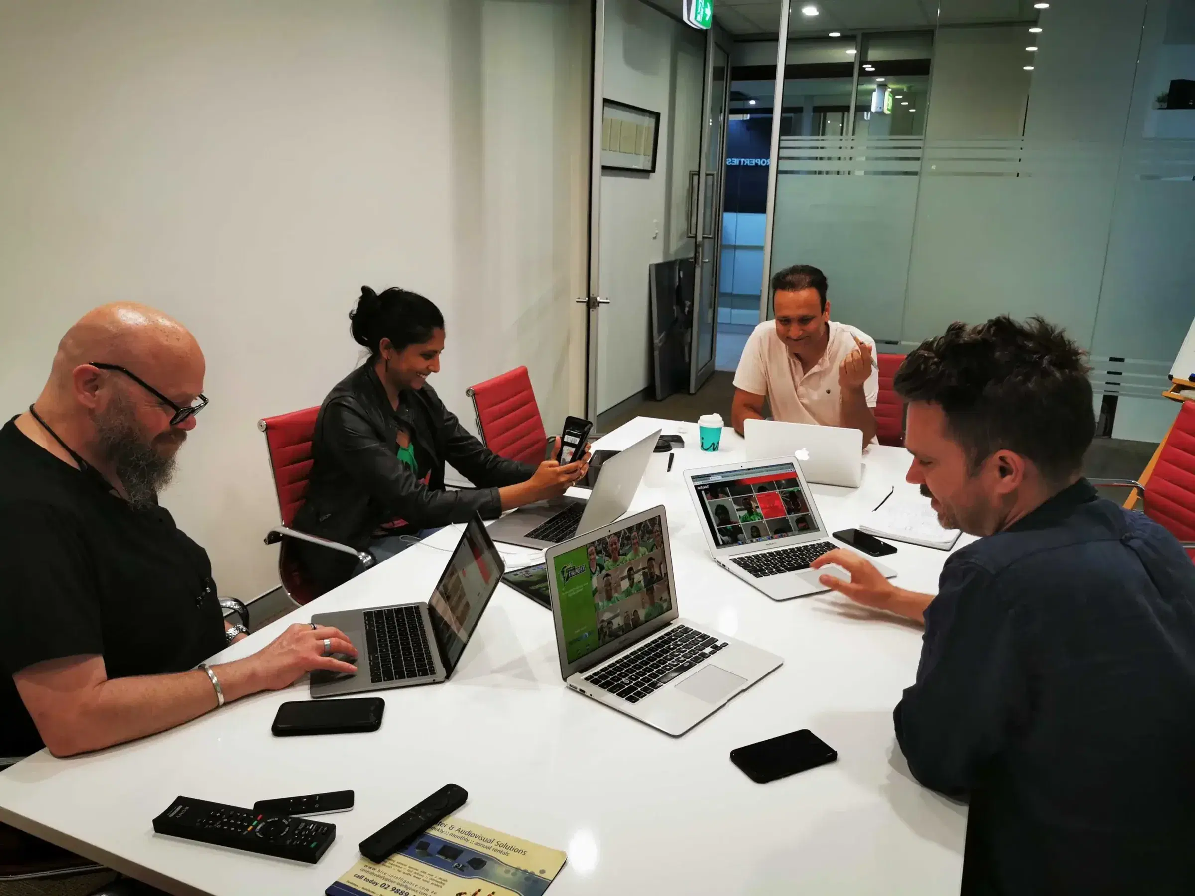 Four Mobiddiction staff working on laptops around a meeting-room table