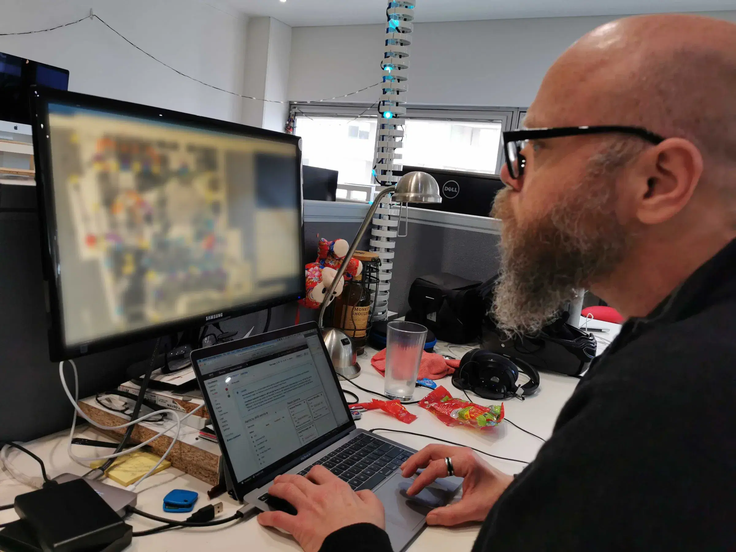 A Mobiddiction engineer at his desk working through a monitoring console on a laptop, beside a second monitor
