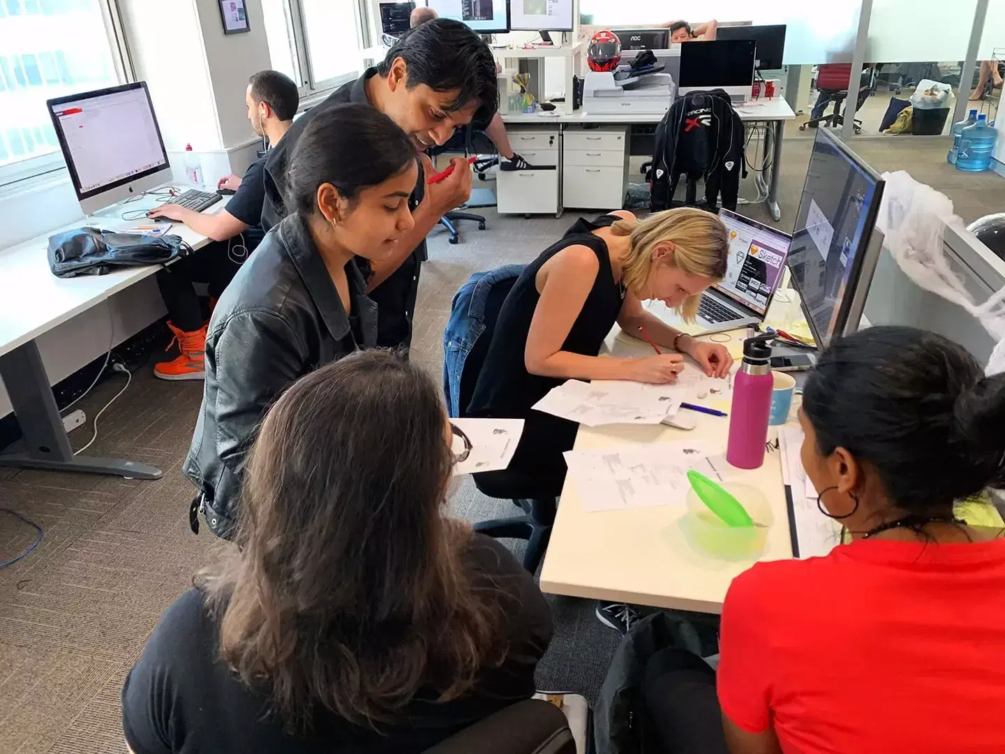 Mobiddiction designers sketching app screens together around a desk in the Sydney office