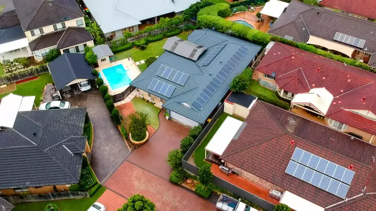 Drone view looking down on suburban houses, gardens and a backyard pool